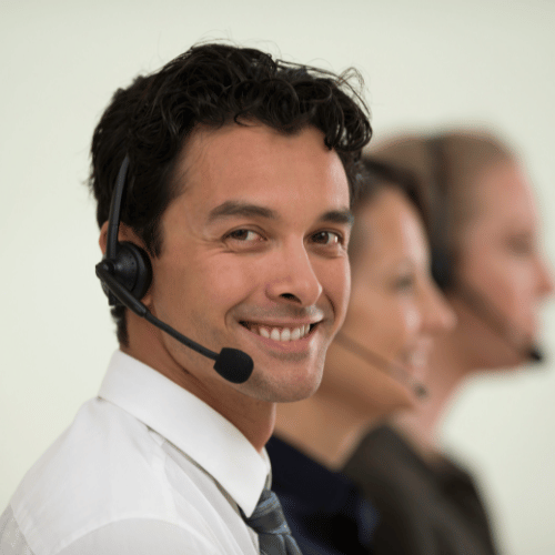 A customer service agent smiling at the camera wearing headsets.