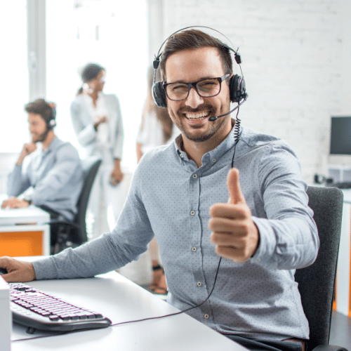 Customer support agent giving a thumbs up at the camera and smiling.