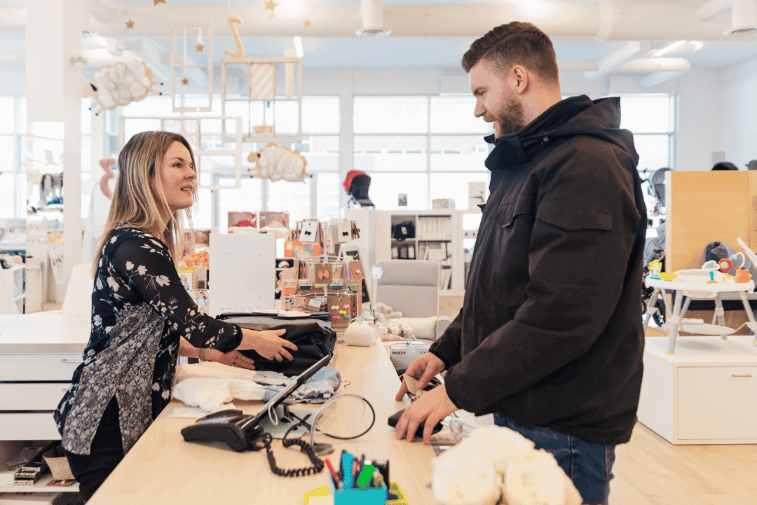 Customer making a purchase from a friendly and patient customer service representative at a store checkout counter.